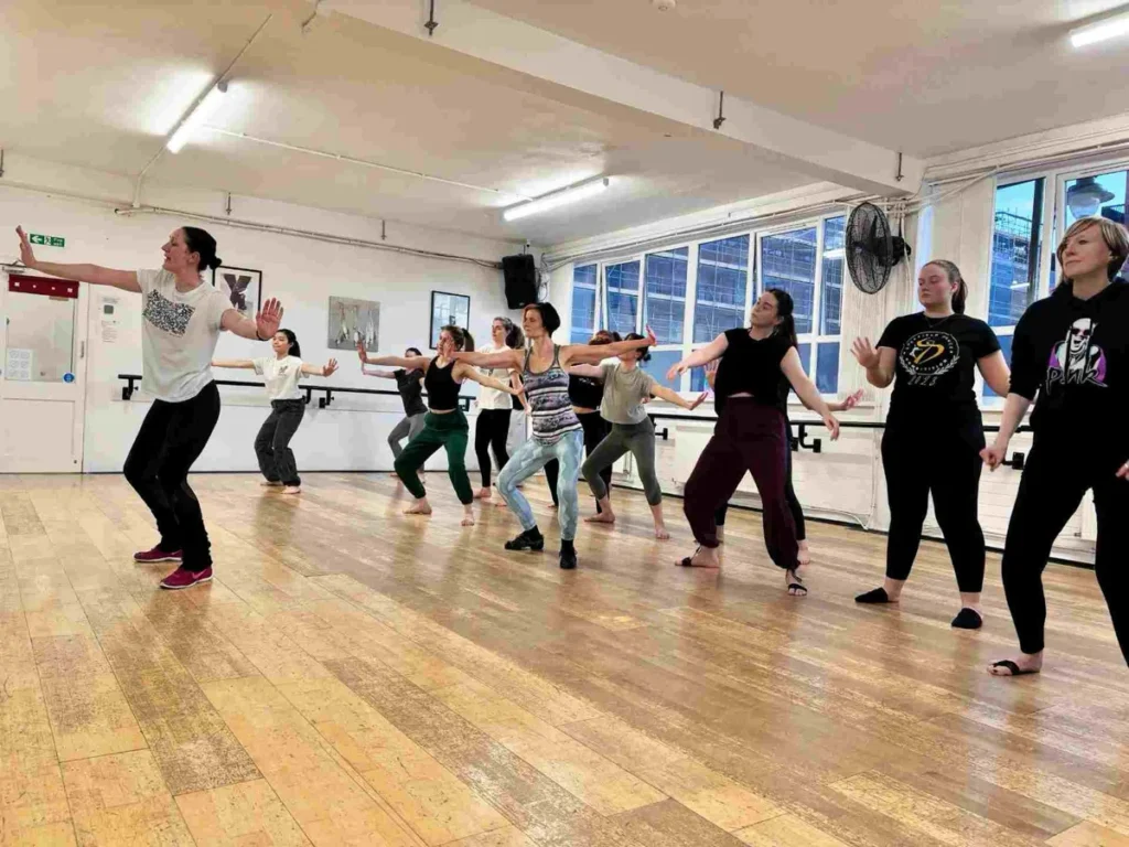 Home 7 Adults dancing together in a modern jazz class at Hype Dance's Sheffield studio, stepping forward with their arms stretched out