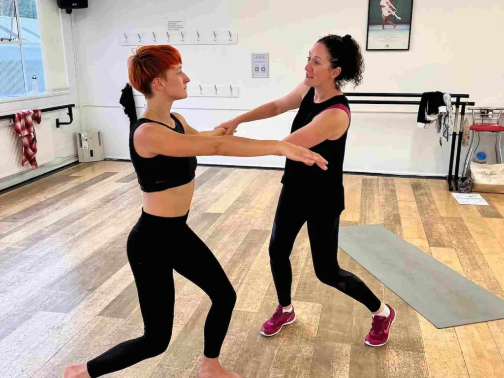 Home 10 A teacher guiding a student by the arm as they lunge together in a private dance lesson at the studio